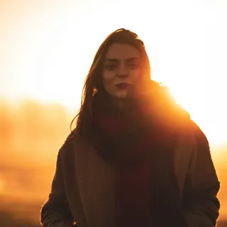 Person standing against a bright sunset sky